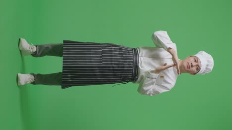 cuerpo lleno de cocinero hombre asiático mirando a la cámara y mostrando tiempo fuera manos gesto mientras estaba de pie en la pantalla verde estudio de fondo