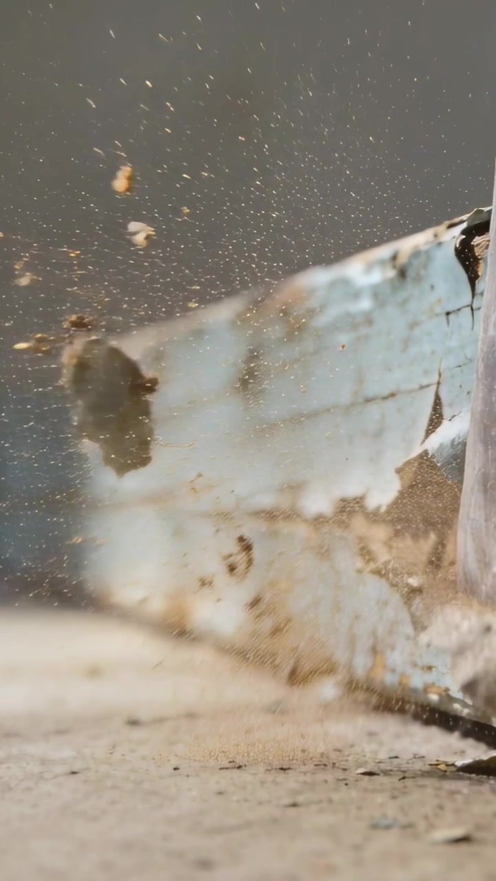 Vertical video: Prying hand using pry tool at peeling blue ledge, removing loose paint on concrete