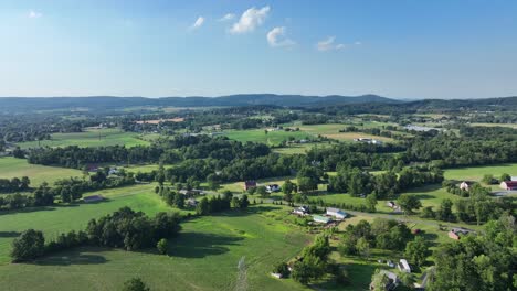 flying over the lush green rural countryside with fields and small clusters of houses on a sunny day