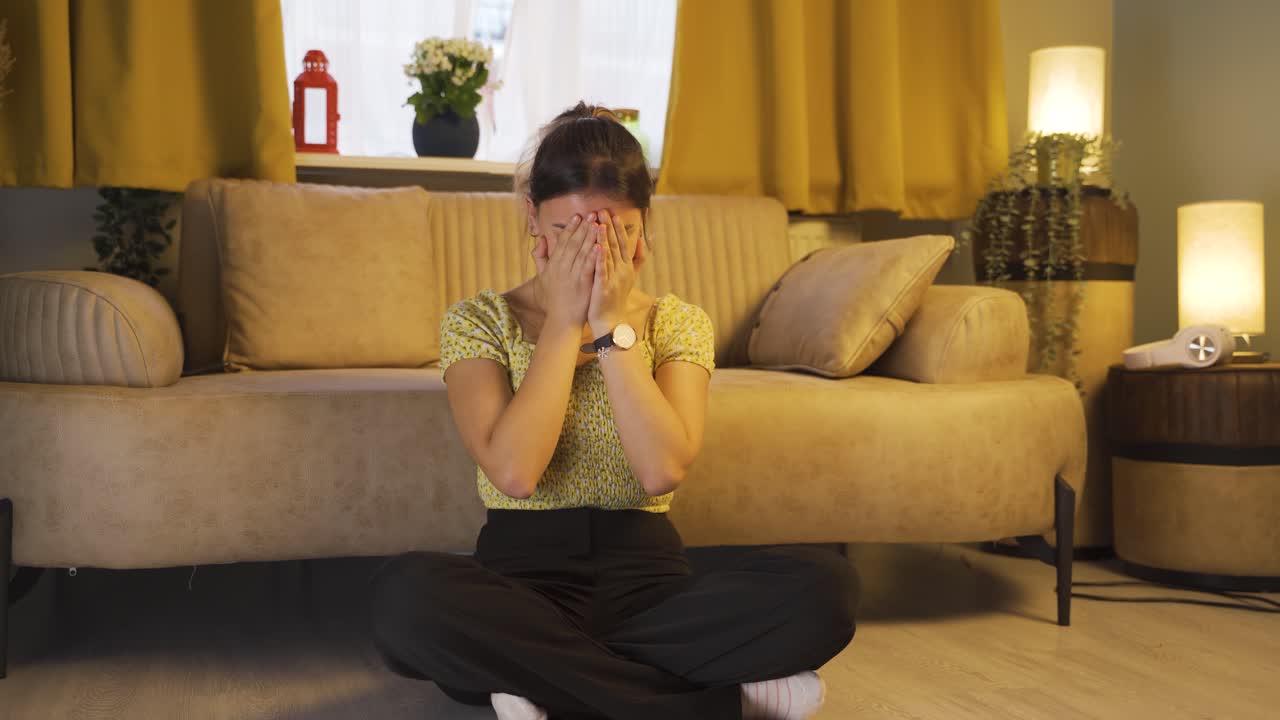 바닥에 앉아 있는 젊은 여성은 울고 있습니다. 절망적입니다.