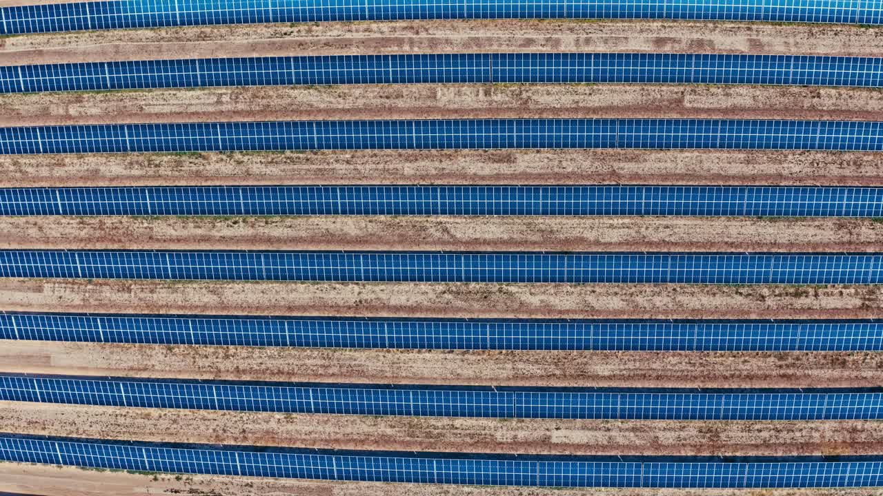 una toma aérea de arriba hacia abajo de filas de paneles solares en una gran granja solar