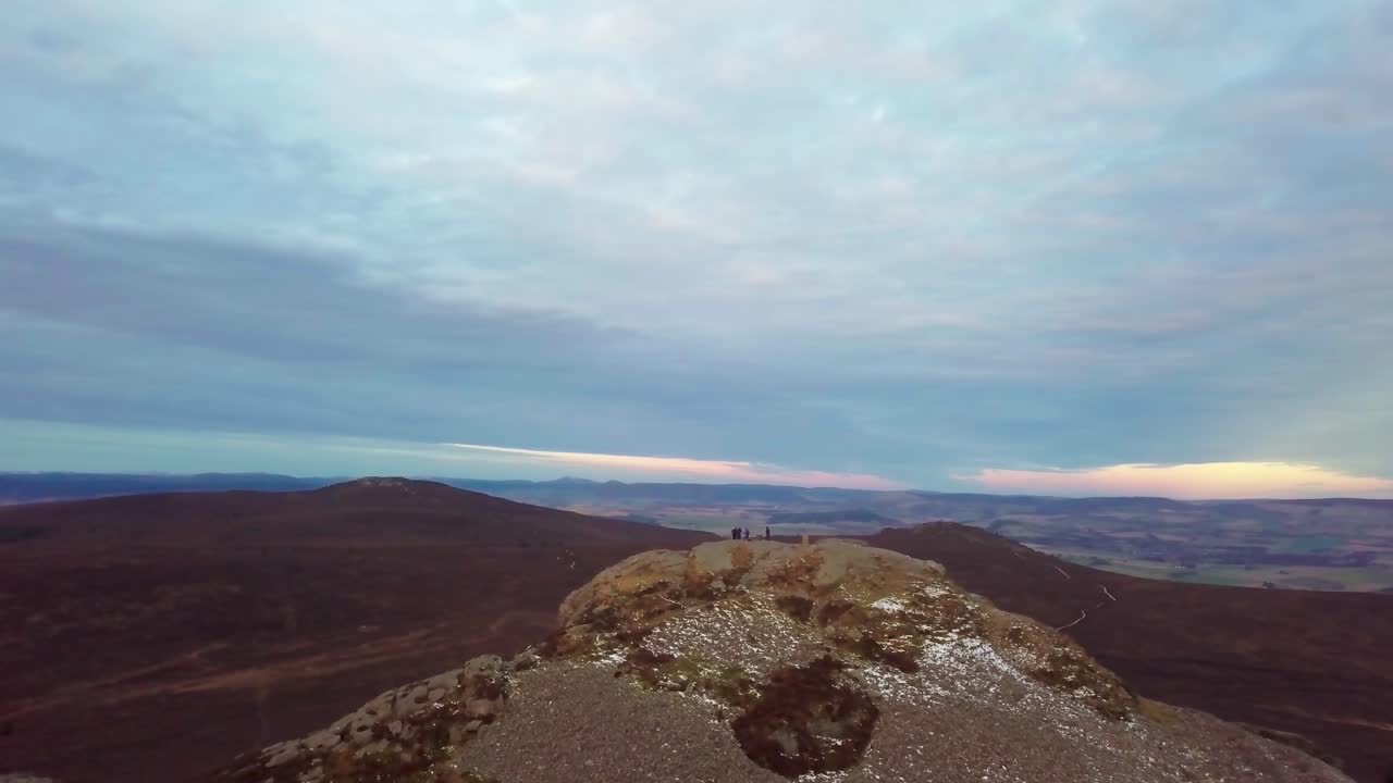 A panoramic view from the top of a rocky hill in Scotland, with distant mountains
