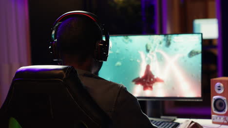 man playing sf space videogame on pc screen in dark room