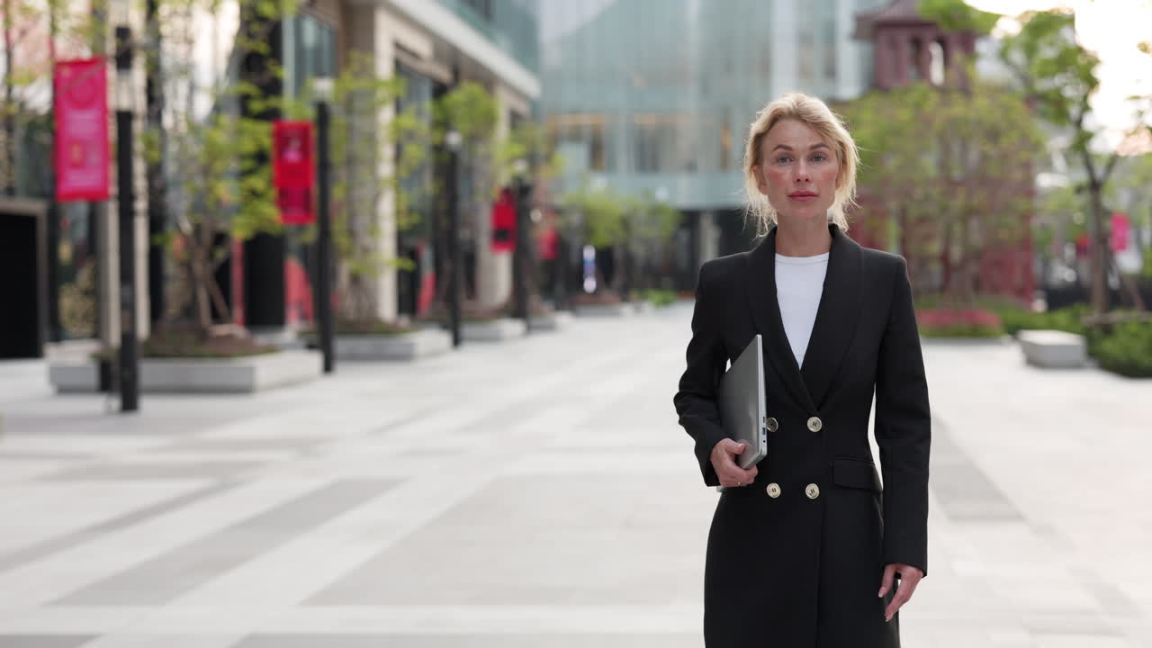 Businesswoman with laptop in city street