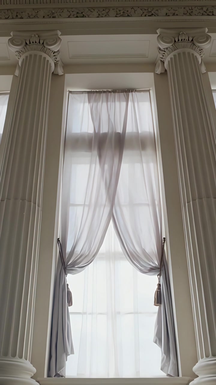 Vídeo vertical: Corrente de ar levantando cortina transparente, ondulando enquanto a câmera inclina para cima, revelando a cornija.