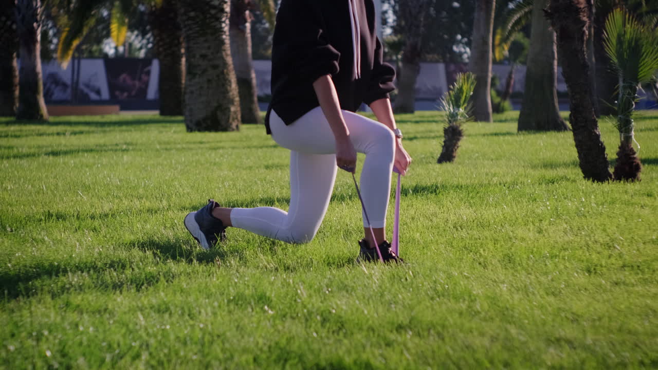 공원에서 저항 밴드로 다리 운동을 하는 여자