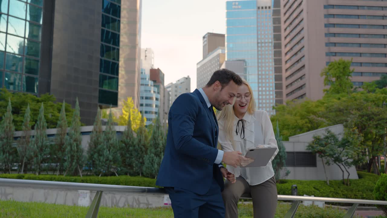 Two Office Workers Colleagues Celebrating Good News on Digital Tablet, Excited Coworkers Surprised by Good Unbelievable News, Unexpected Win, Huge Bonus Looking at Tablet Screen Feeling Amazed