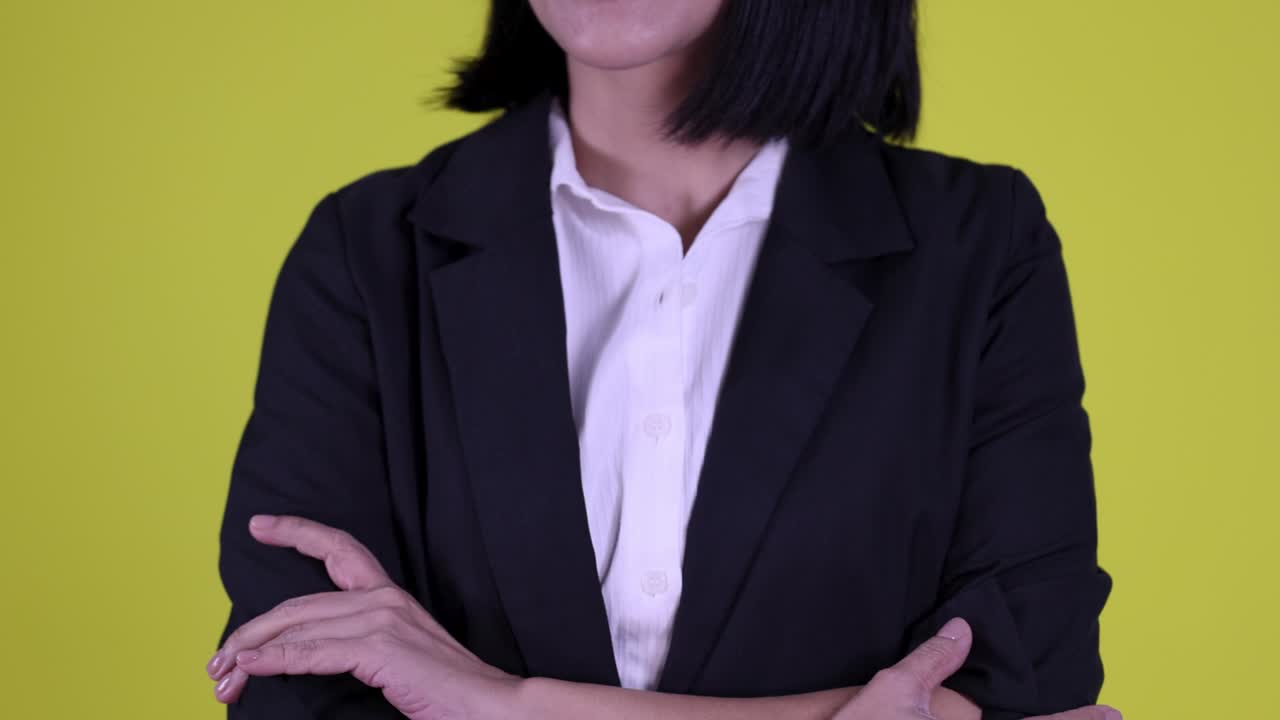 Una professionista in posa sicura, a braccia conserte, su uno sfondo giallo acceso in studio