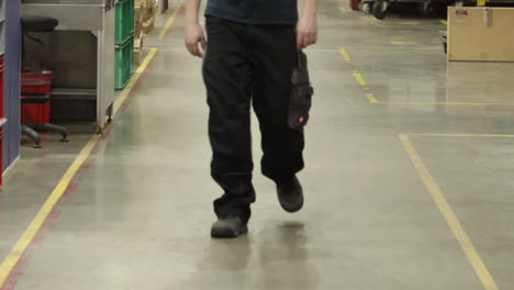 worker-walking-alone-inside-a-factory-industrial-warehouse-reaching-the-production-line-following-the-safe-area-inside-yellow-line-on-the-ground