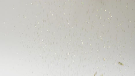 Video-of-glittering-gold-confetti-falling-on-white-background