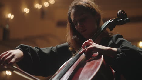 cellist on scene of philharmonic hall concert of classical music closeup view of cello and bow