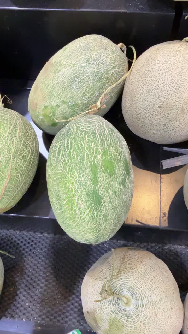 Hand Picking a Fresh Green Melon in a Grocery Store