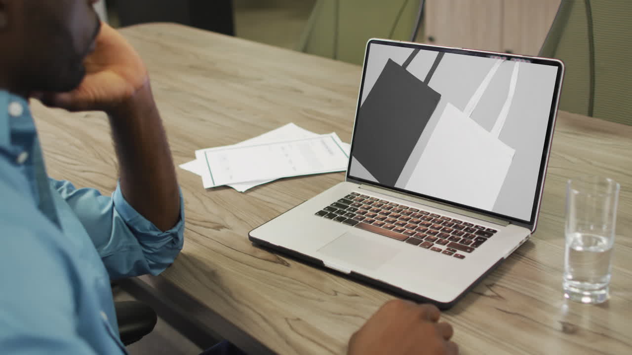 African american man using laptop at table, online shopping for bags, slow motion