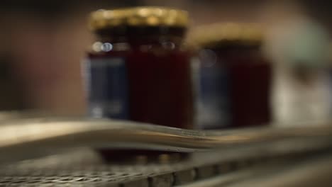 line of filled jam jars moving on a conveyor belt in a factory for selling