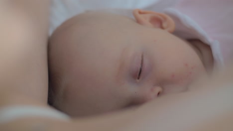 sleepy baby girl being breastfed by her mother