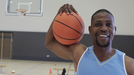 Retrato-De-Un-Jugador-De-Baloncesto-Afroamericano-Sosteniendo-Una-Pelota-En-Una-Cancha-Cubierta,-En-Cámara-Lenta