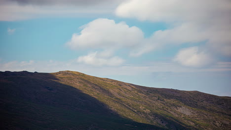 Eine-Zeitrafferaufnahme-Einer-Sanften-Windscherung,-Die-Wolkenschatten-Auf-Einem-Berggipfel-Bildet