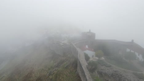 a drone flies through the mist above marvão castle and the nearby town