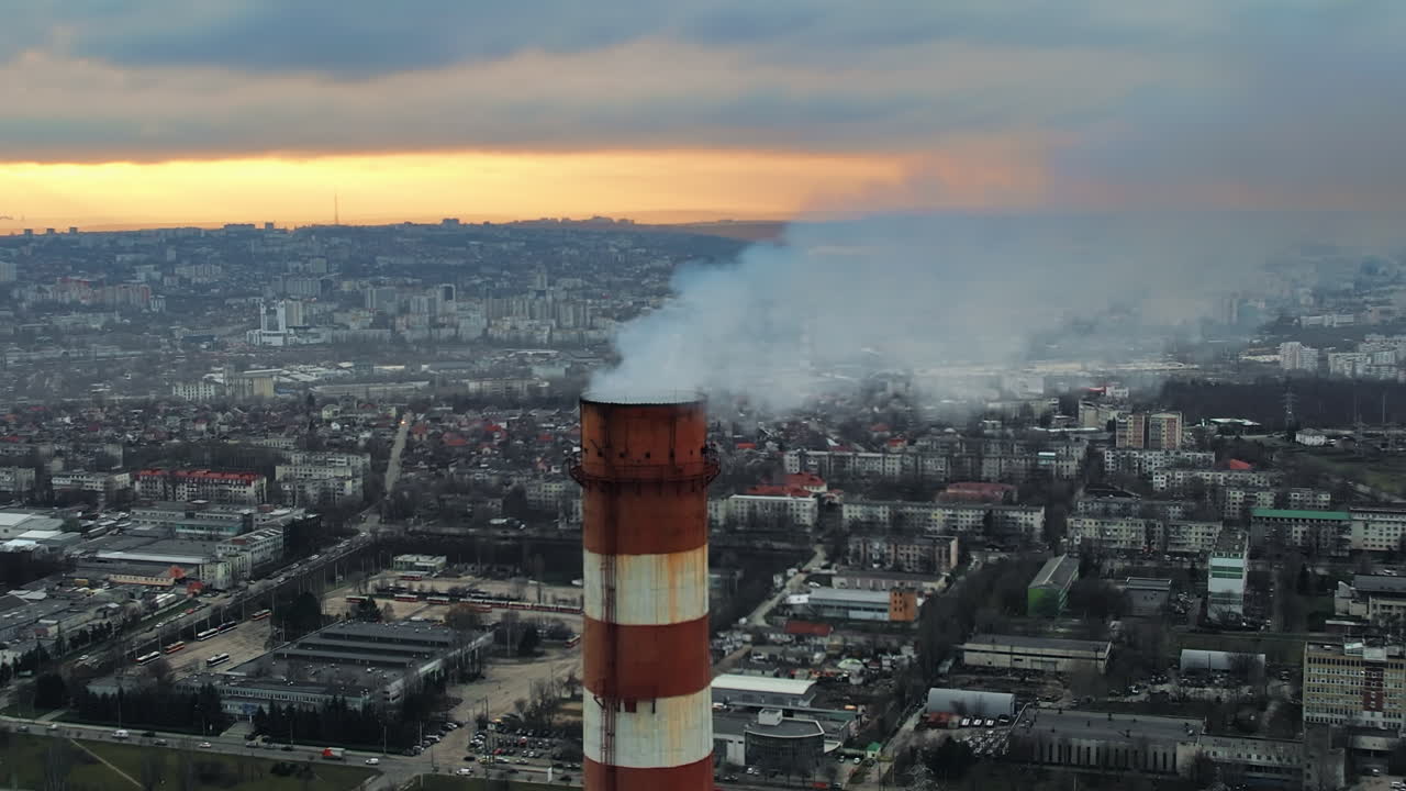 Aerial drone view of thermal power plant in Chisinau at cloudy weather, Moldova. View of pipes with felling steam, cityscape, sunset