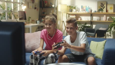 two happy kids playing video games on a couch