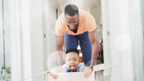 Animation-of-bokeh-over-happy-african-american-father-and-son-having-fun-at-home