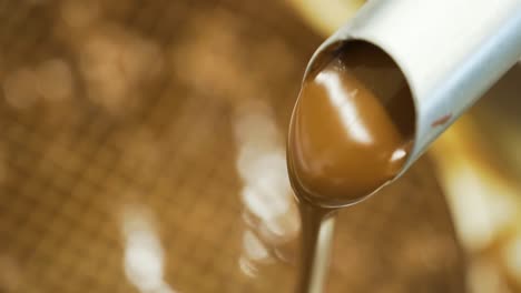 Closeup-shot-of-creamy-chocolate-flowing-through-a-pipe-at-a-cake-making-factory