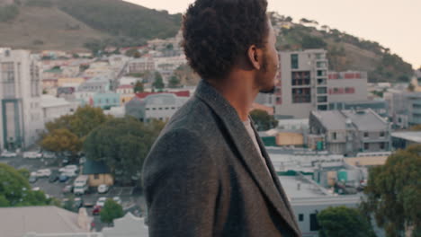 Attraktiver-Junger-Afroamerikanischer-Mann-Genießt-Den-Blick-Von-Der-Dachterrasse-Auf-Die-Skyline-Der-Stadt-Bei-Sonnenuntergang,-Lächelt-Glücklich-Und-Trinkt-Erfrischendes-Kaltes-Bier-Und-Feiert-Die-Wochenendparty