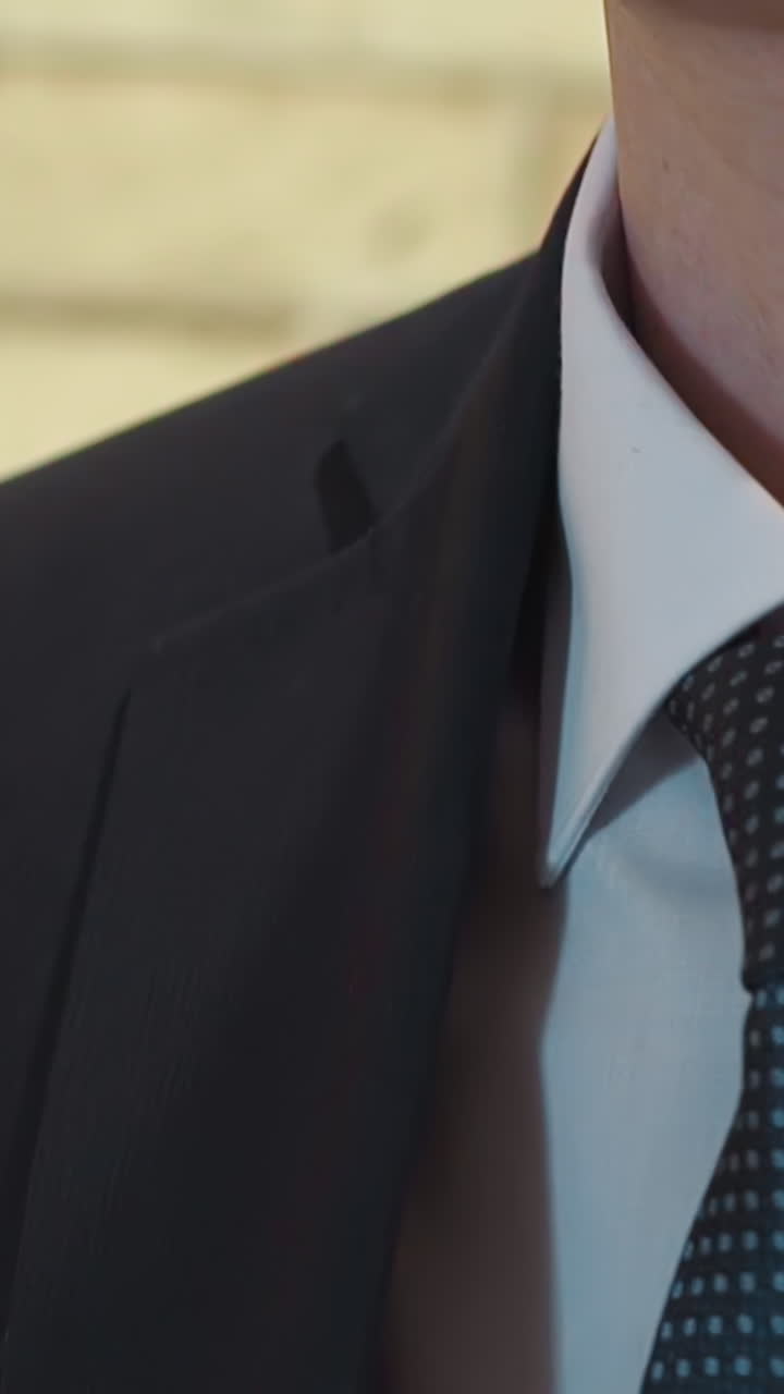 Stylish groom in shirt with tie puts on suit jacket preparing for wedding ceremony closeup slow motion. Elegant clothes for festive events. Men apparel