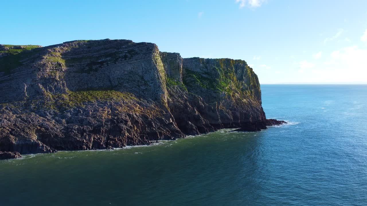 Slow Aerial of Seascape with Steep Rugged Cliffs with Calm Ocean. Travel Nature Drone Clip. Beautiful Welsh Gower Peninsula Coast