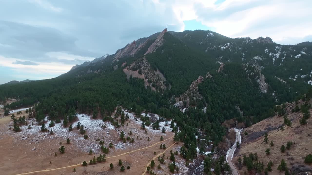 A panoramic aerial of Boulder Flatirons landscape, with sunlit cliffs and forested surroundings