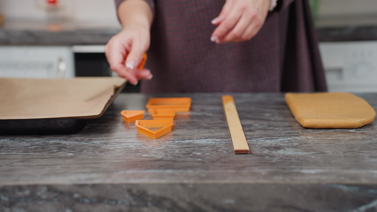 primer plano de un panadero colocando formas de horneado de naranja en la encimera con papel marrón al lado, preparándose para la creación de pasteles en un entorno de cocina moderno