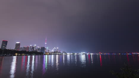 Lapso-De-Tiempo-De-Amanecer-Lluvioso-Y-Nublado-Con-El-Horizonte-Del-Centro-De-Toronto-A-Través-Del-Agua-Desde-El-Parque-Trillium