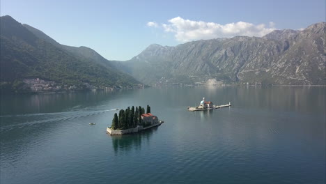 aerial shot of man made islands in montenegro with mountains in the distance