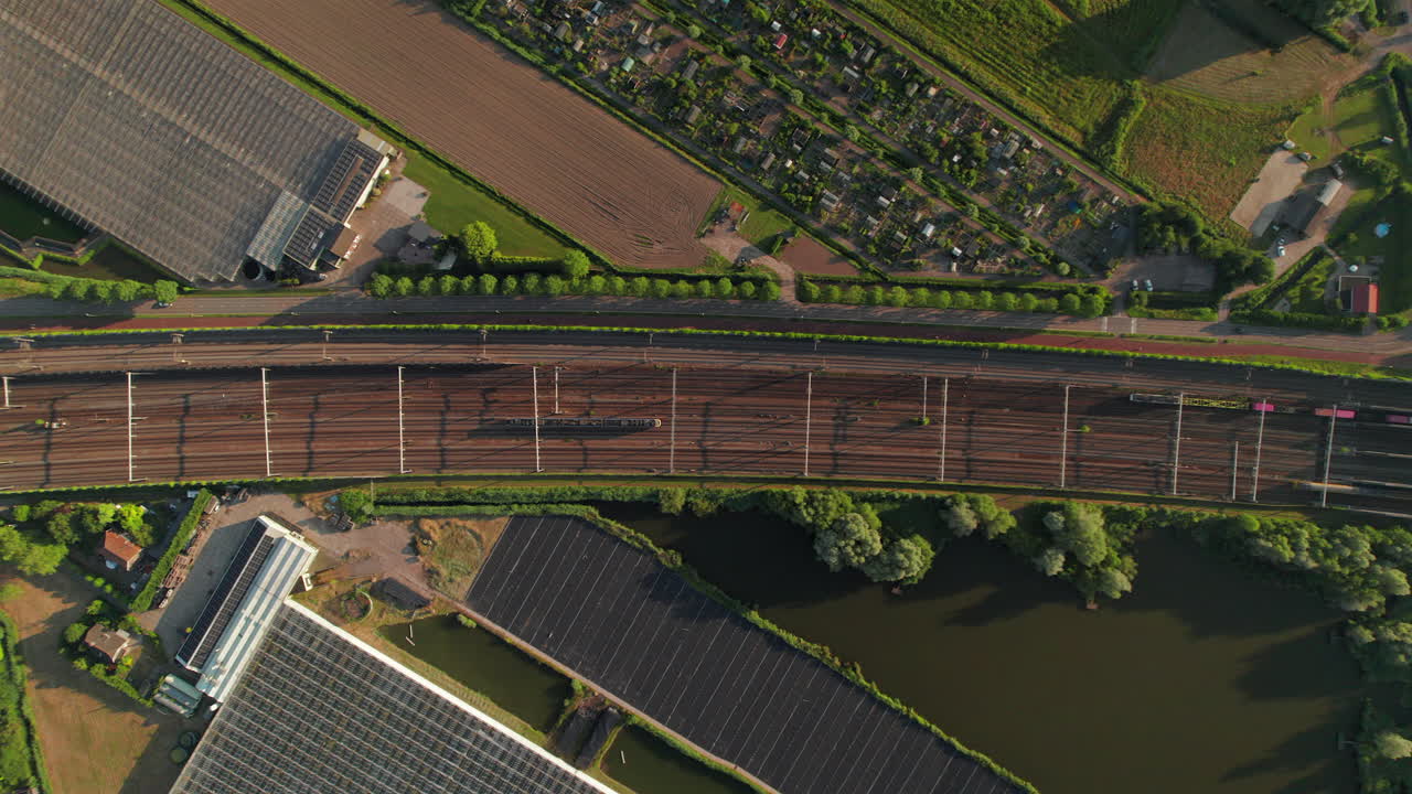 Aerial View of Train Tracks Surrounded by Greenhouses and Farmland