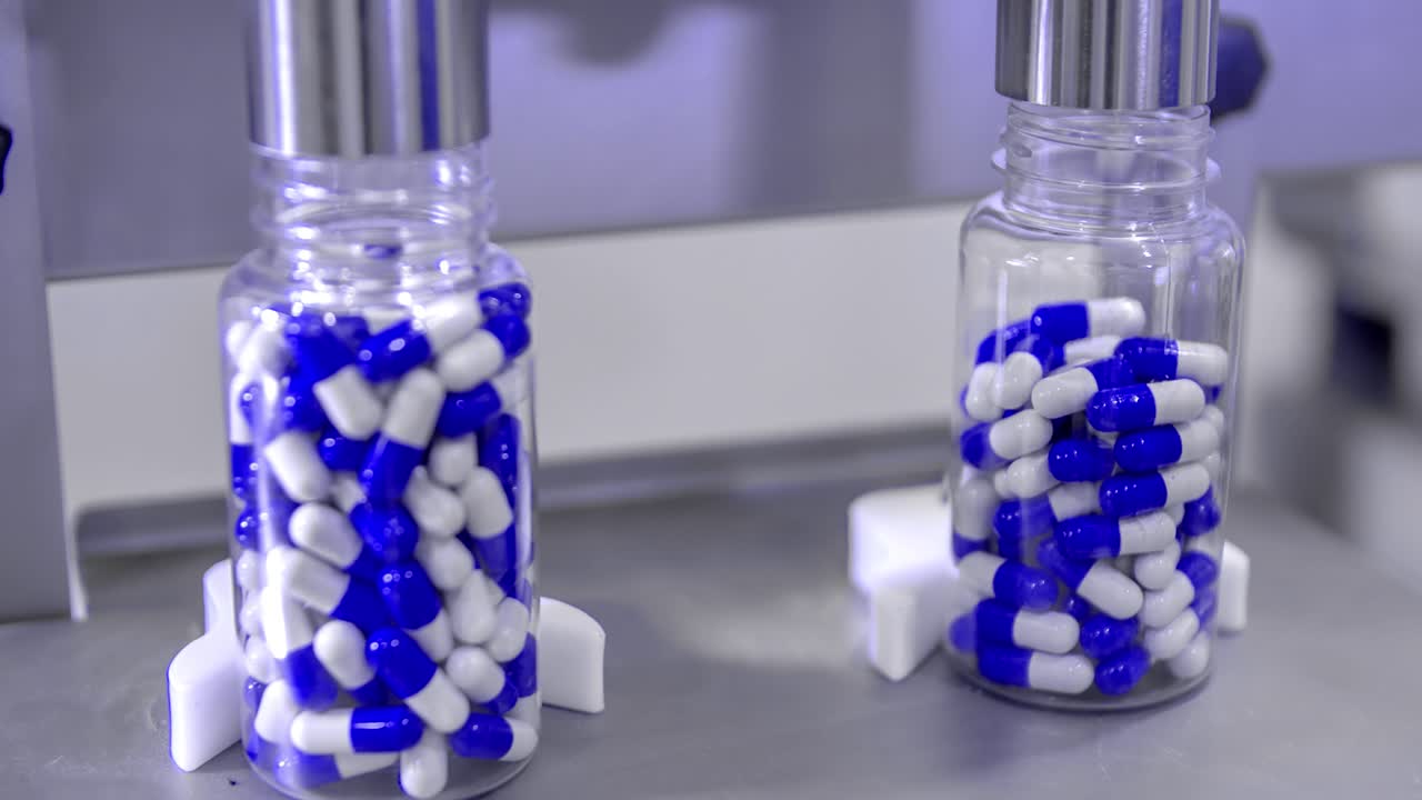 Piccole boccette per pillole che vengono riempite durante la produzione di massa di cure per il COVID-19