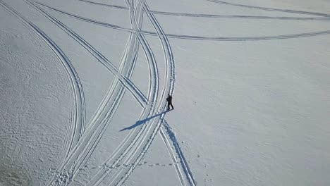 Toma-Aérea-Giratoria-Del-Hombre-Que-Opera-Un-Dron-En-Un-Paisaje-Invernal-Nevado