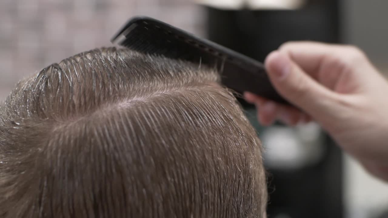 Barbiere che pettina e acconcia i capelli di un uomo.