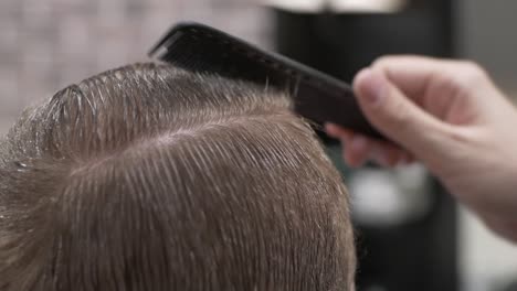 barbero peinando y peinando el cabello de un hombre