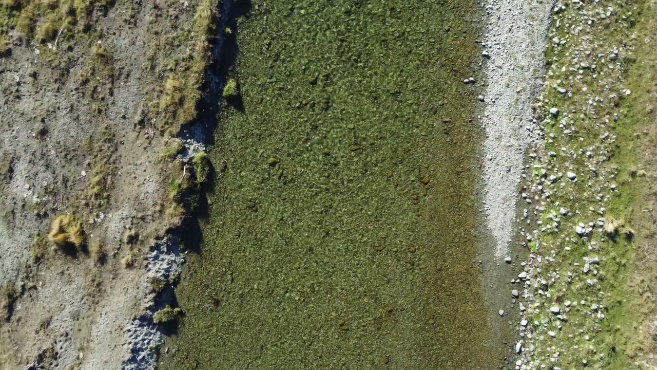 vista aérea sobre un río claro que fluye sobre un lecho de grava con orillas cubiertas de hierba