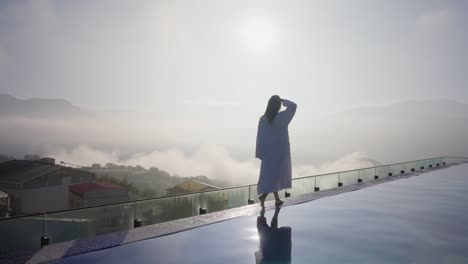 woman walking by the side of the pool in the morning at luxury hotel