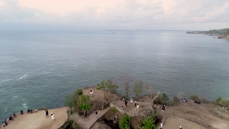 Aerial Fly Over Green Rock Cape With Waves and Cloudy Day at Balangan Beach Bali Indonesia Asia