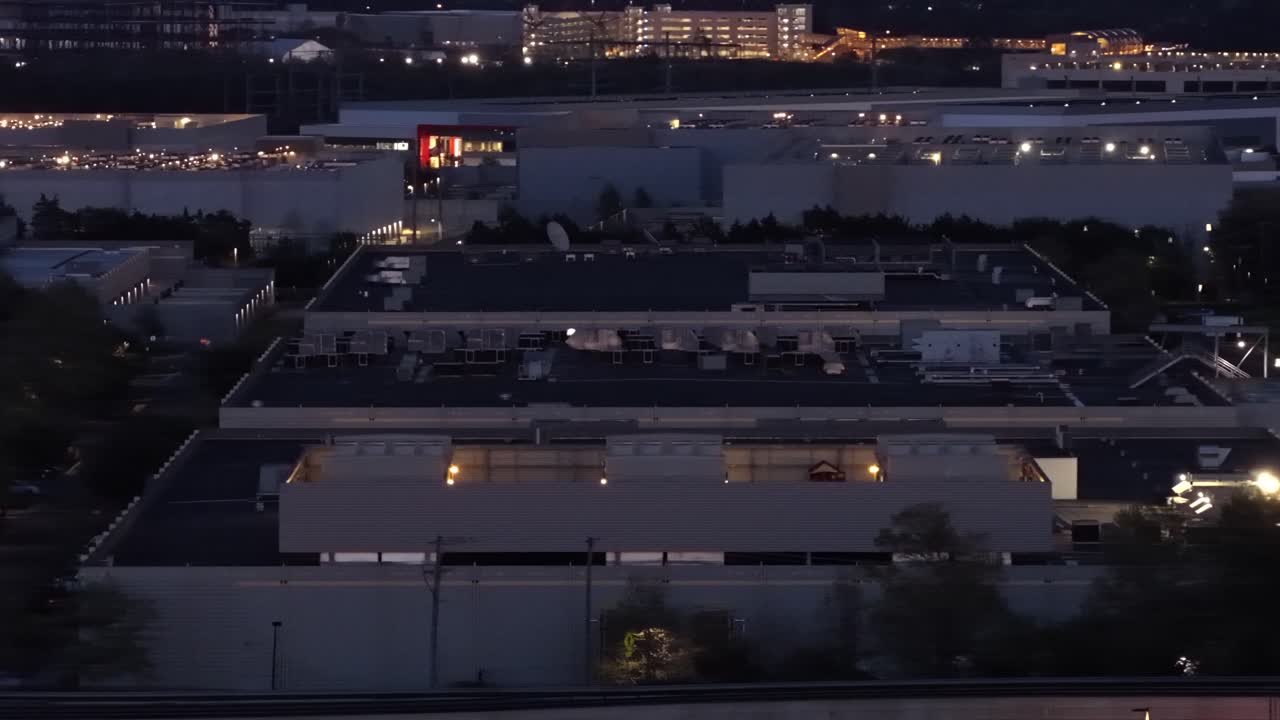 Luftfoto af datacenter campus i Ashburn, Virginia, USA i skumringen med oplyste bygninger, taginfrastruktur og glødende lys, der fremhæver cloud computing og digitale netværksoperationer.