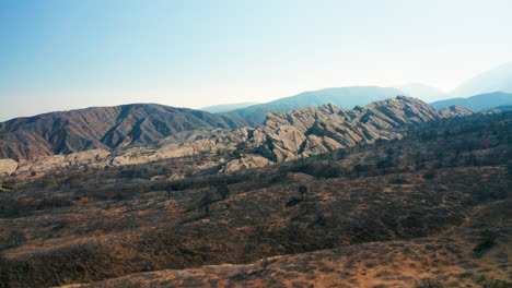 Ascending-tilt-down-aerial-view-of-mountains-and-foothills-burned-to-ash-by-seasonal-wildfires-in-Southern-California