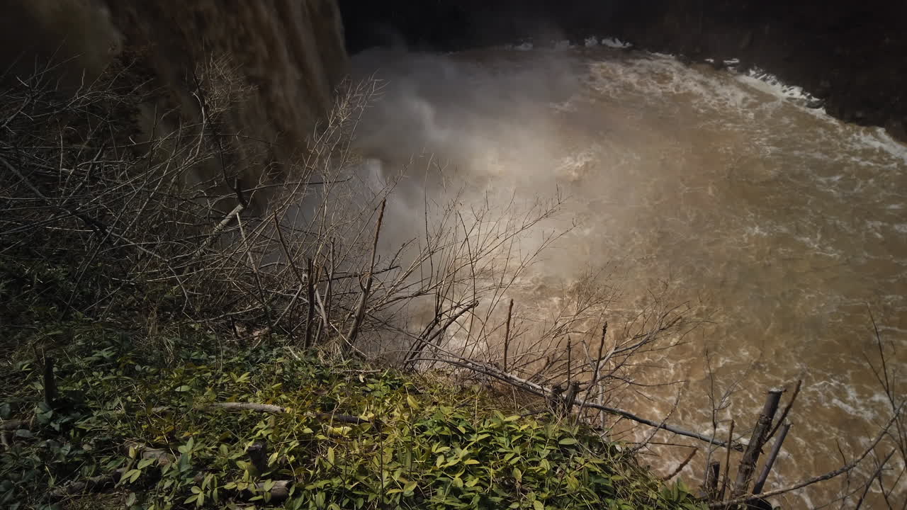 Wide shot with tilt up from a misty river to the top of Balls Falls