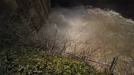 wide shot with tilt up from a misty river to the top of balls falls