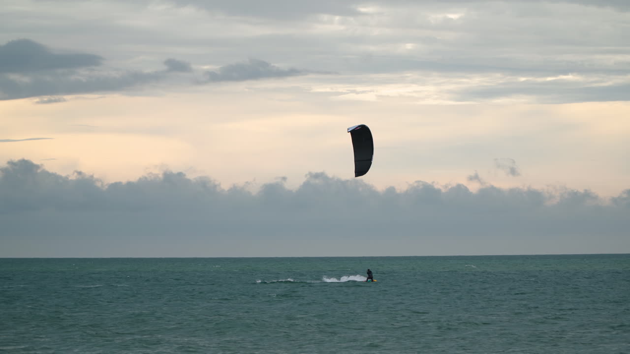 el hombre kitesurfer salta y cae al agua mientras practica kitesurf al atardecer colorido con cielo nublado en kota kinabalu - estática de gran angular