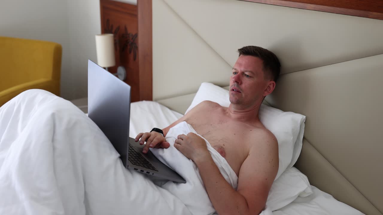 hombre trabajando en la computadora portátil en la cama