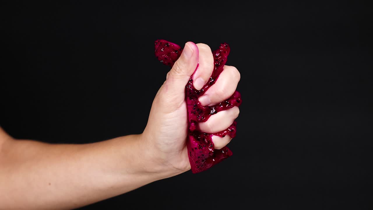 la mano apretando la fruta del dragón, el jugo goteando