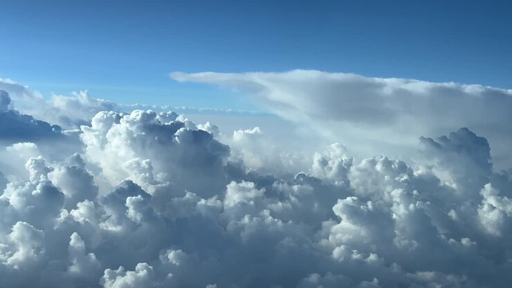Pilot POV flying in a blue sky full of stormy clouds shot from an airplane cockpit at cruise level