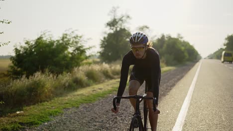 male cyclist in helmet rides bicycle along the track, closeup